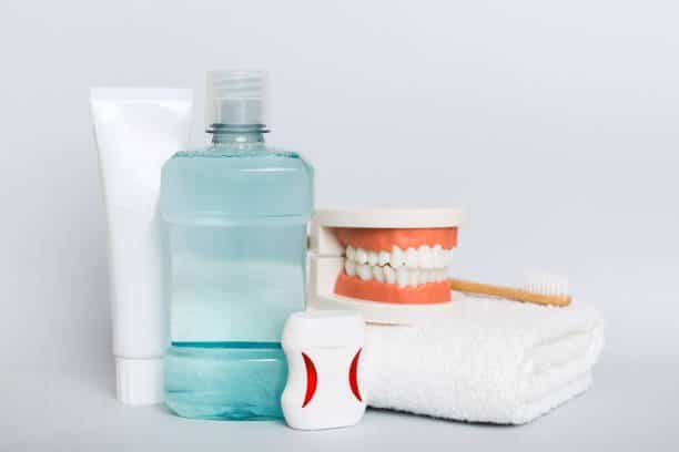 Conjunto de produtos de higiene bucal, incluindo escova de dentes, fio dental, creme dental e enxaguante, representando os cuidados essenciais para facetas de porcelana.