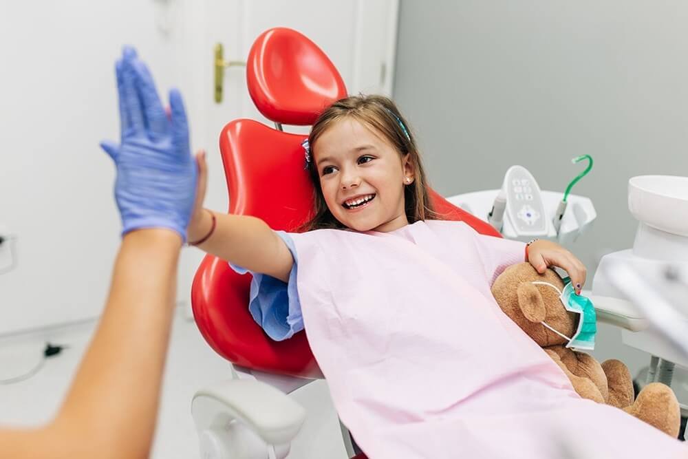 Criança sorrindo no consultório durante atendimento de odontopediatria